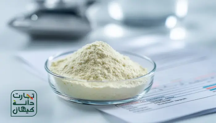 نمای نزدیک از پودر چربی دام در یک ظرف شیشهای آزمایشگاهی، قرار گرفته روی میز سفید همراه با برگه آنالیز و نتایج ترکیب خوراک؛ تصویری مناسب برای موضوع کیفیت و ارزیابی آزمایشگاهی پودر چربی.